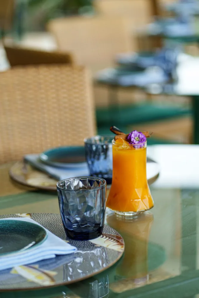 Cóctel naranja decorado con una flor sobre una mesa en una terraza